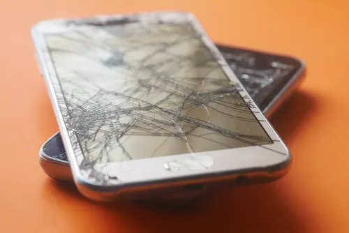 Cracked smartphone screen being repaired by technician